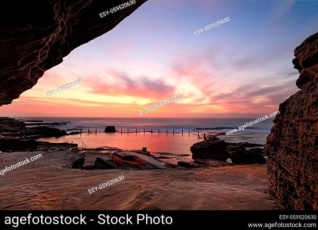 Sensational sunrise at Mahon rock pool, Maroubra, bathing the rocks and pool in vibrant reds and pink hues while a cave adds some interesting textures and...