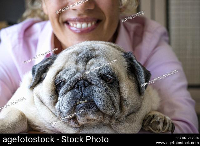 Happy woman hug his dog pug with love and frienship . concept of best friend forever and animal owner enjoying time at home - close up of affection and joyful...
