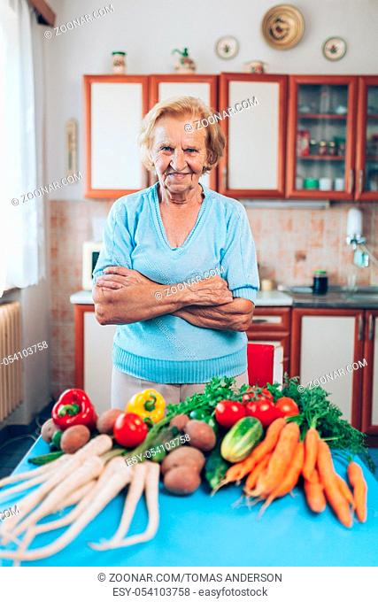 Happy senior woman at home with fresh crop from her garden