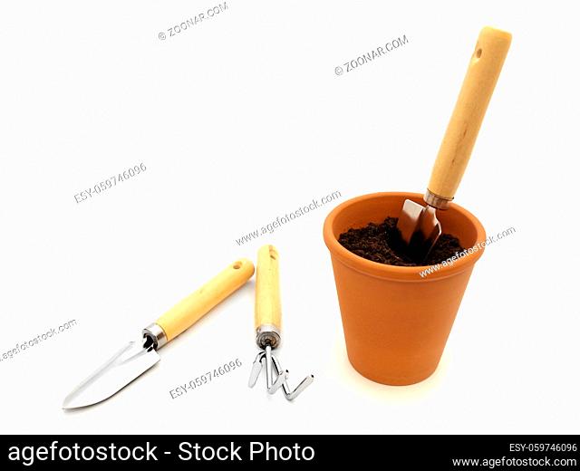 Gardening Trowel In Pot With Black Soil Against White Background