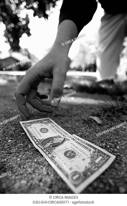 Man Picking Up Dollar Bill From Ground