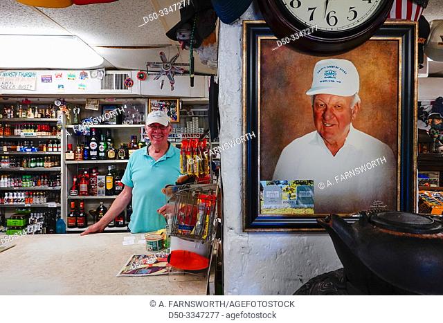 Point Lookout, Maryland USA A liquor store owner behind the counter with a picture of his father