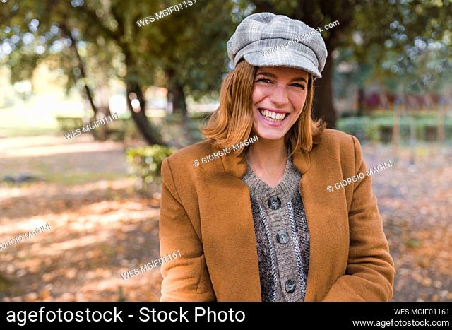 Mujer joven feliz con boina en el parque de otoño