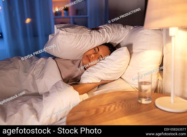 angry african woman lying in bed and closing ears