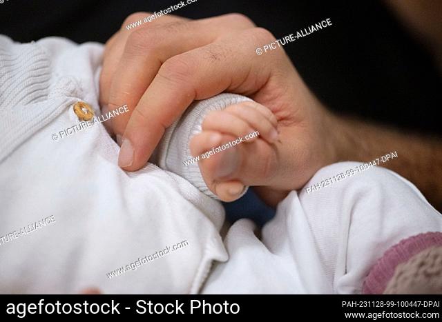 SYMBOL - 24 November 2023, Baden-Württemberg, Stuttgart: A father holds his child's hand during an infant handling course