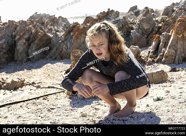 Teenage girl collecting shells on a sandy beach