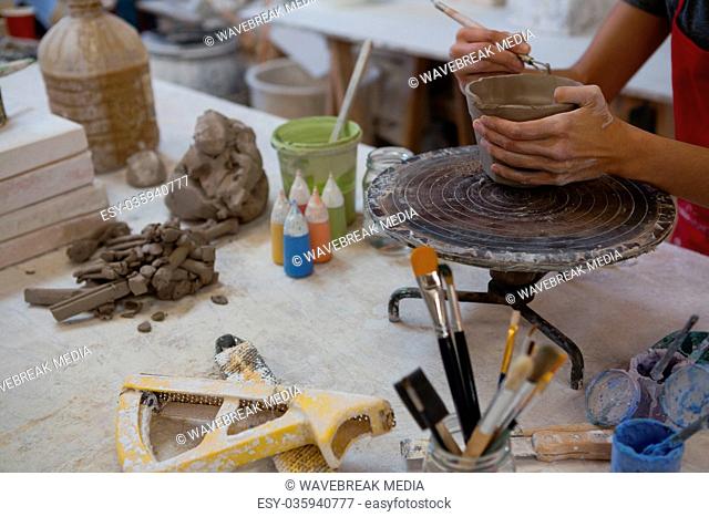 Female potter molding a mug with hand tool