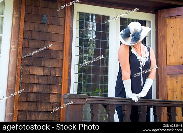 Attractive Young Woman in Twenties Outfit on Porch of an Antique House