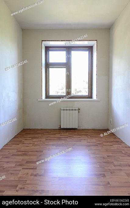 View of the window in a small room after renovation, wood-effect laminate is laid on the floor
