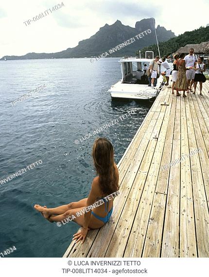 French Polynesia, Bora Bora. Woman sitting on pier