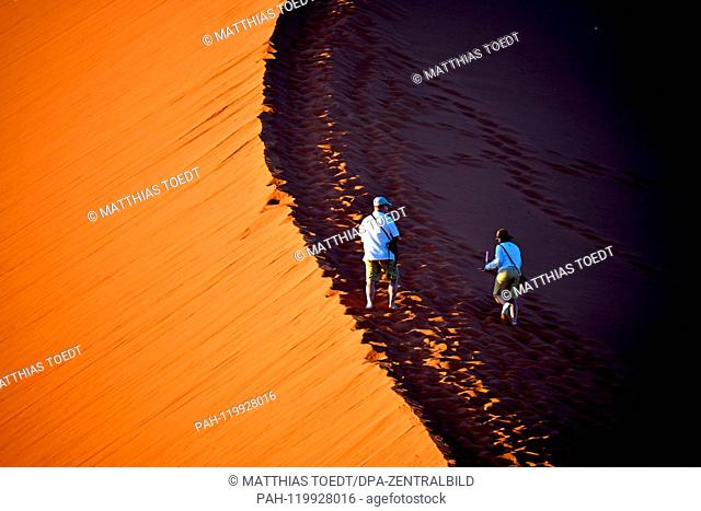 Tourists begin the rise of a dune in Sossusvlei shortly before sunrise, taken on 01.03.2019. The Sossusvlei in the Namib-Naukluft National Park has been a...