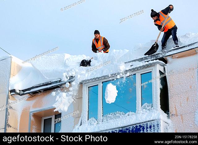 PETROPAVLOVSK CITY, KAMCHATKA PENINSULA, RUSSIA - DEC 27, 2017: Worker with snow shovel carry out winter cleaning of roof of building from snow and ice after...