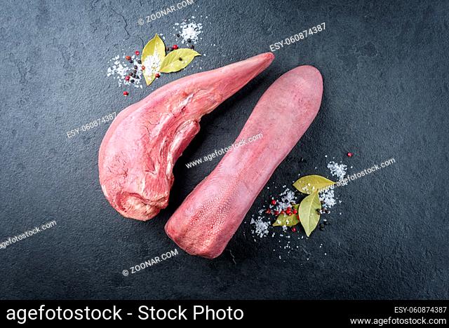 Traditional cooked beef tongue with spice offered as close-up on a rustic black board