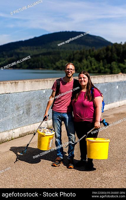 PRODUCTION - 06 July 2022, Baden-Wuerttemberg, Forbach: René Engels and his girlfriend Michaela stand on the Schwarzenbachtalsperre and hold grapple tongs as...
