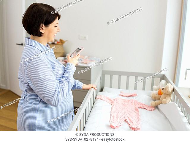 pregnant woman taking picture of baby clothes