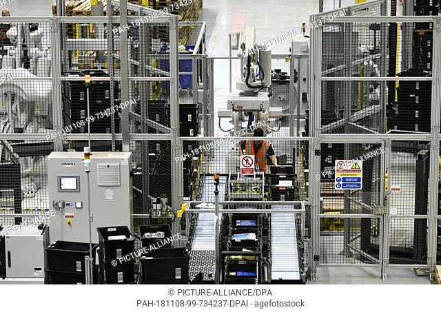08 November 2018, North Rhine-Westphalia, Dortmund: An employee is working on state-of-the-art robot arms in the logistics centre of the mail order company...