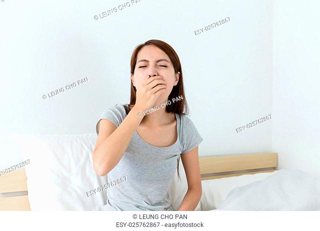 Asian woman yawning on the bed
