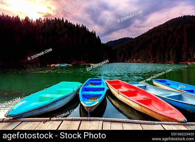 color boats on still mountain lake with forest
