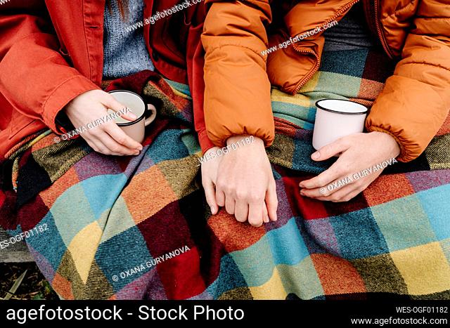 Couple with coffee cups holding hands