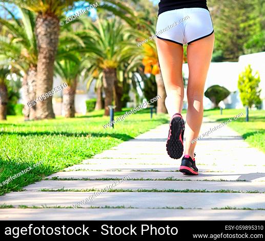 Runner feet running on road in the park. cCloseup on shoes. Woman fitness sunrise jog workout welness concept