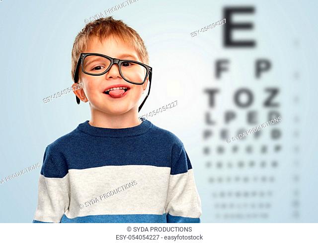 little boy in glasses showing tongue