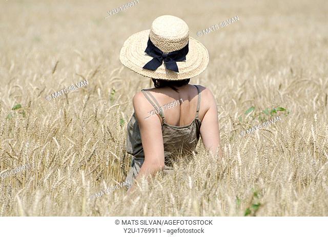 Woman with a straw hat standing up in the wheat field