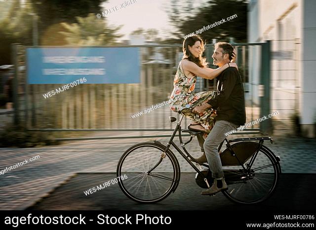 Man riding bicycle with woman sitting on handle