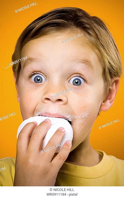 Boy with blue eyes eating donut