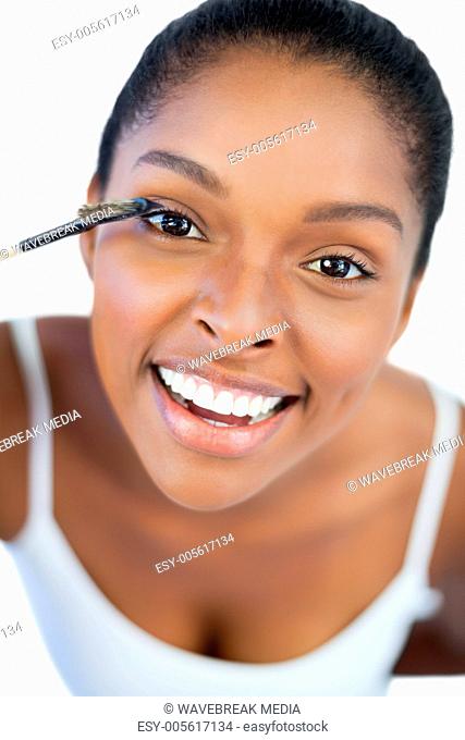 Smiling woman putting mascara on her eyelash