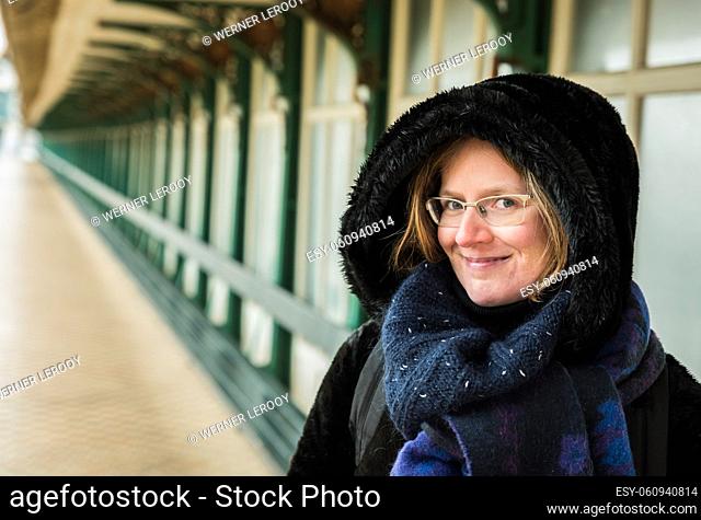 Portrait of an attractive white woman , 30 years old with winter clothes on a windy day at the seaside, Blankenberge, Belgium