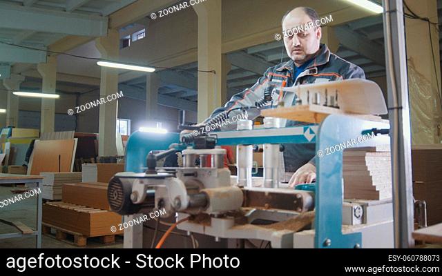Worker carpenter cut a wooden workpiece on a furniture factory, woodworking