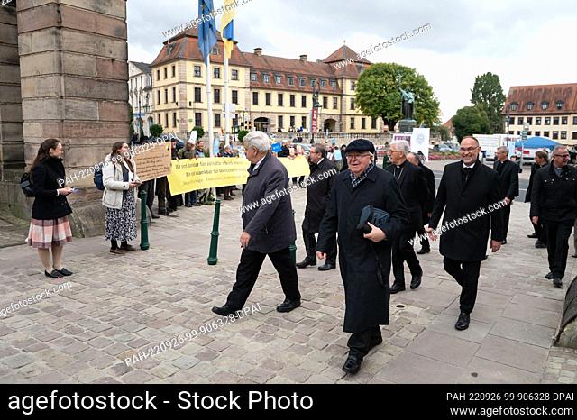 26 September 2022, Hessen, Fulda: Bishops walk past activists of the conservative church movement Maria 1.0 in front of the Fulda City Palace at the start of...