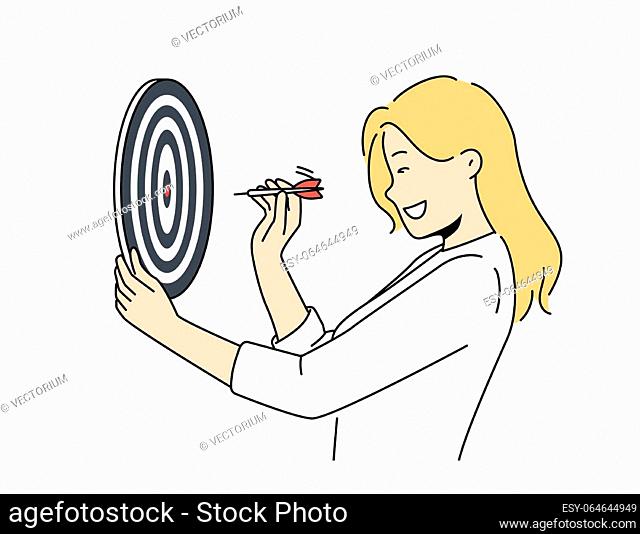 Determined woman throws darts at target for concept of business success and achieving set goals. Goal oriented businesswoman with darts board smiling setting...