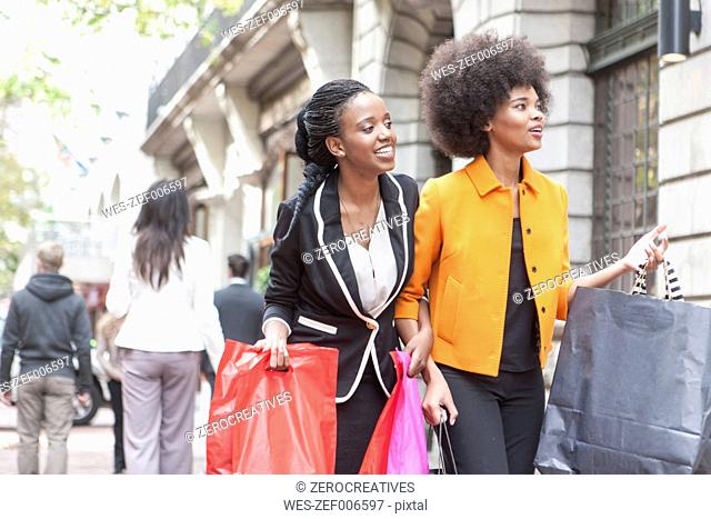Two young women arm in arm on shopping tour