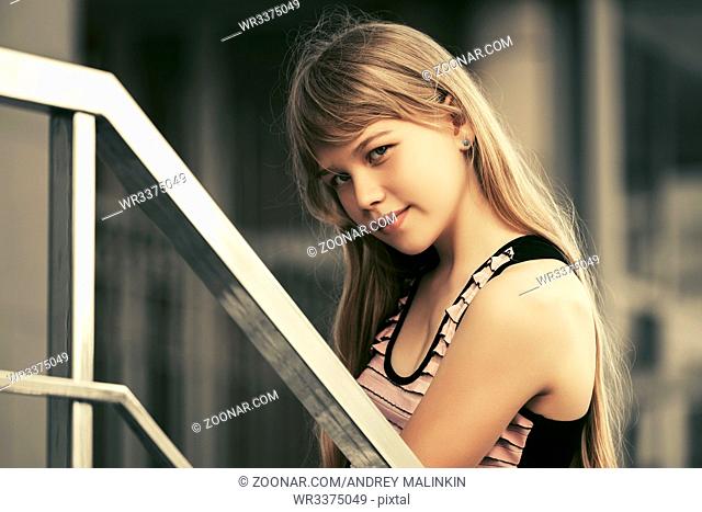 Teen girl in tank top against a school building. Stylish fashion model outdoor