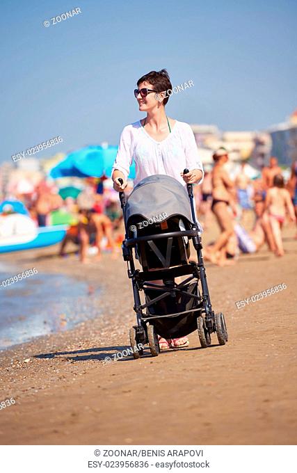 mother walking on beach and push baby carriage