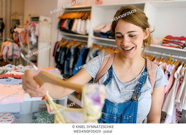 Happy pregnant woman shopping for baby clothing in a boutique