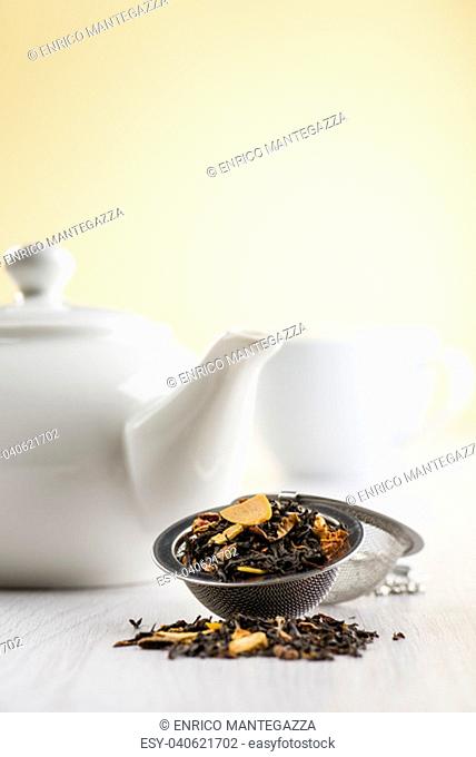 infuser with black tea on table with teapot