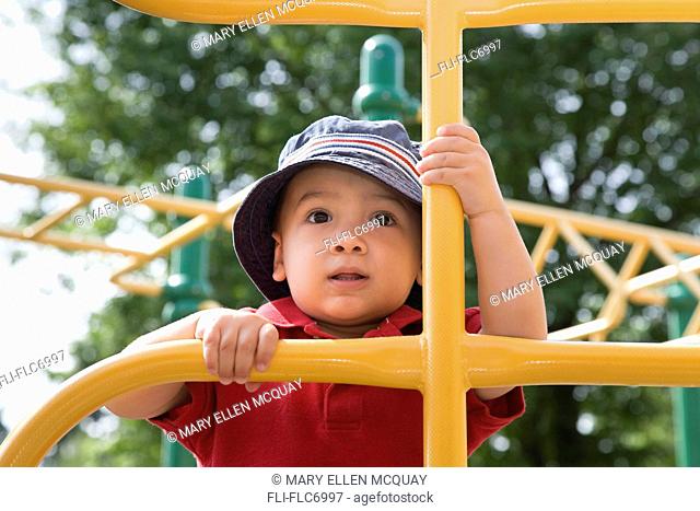 Young Asian-Caucasian boy climbing playground equipment, Ontario, Canada
