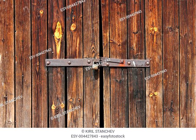 Old Wooden door locked with rusty padlock