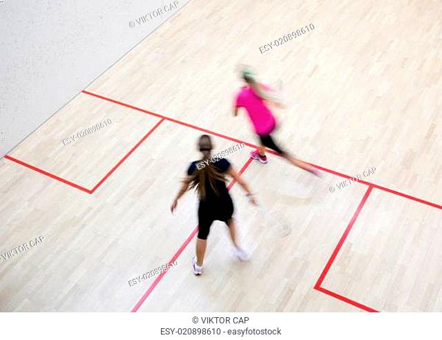 Two female squash players in fast action on a squash court (motion blurred image color toned image)