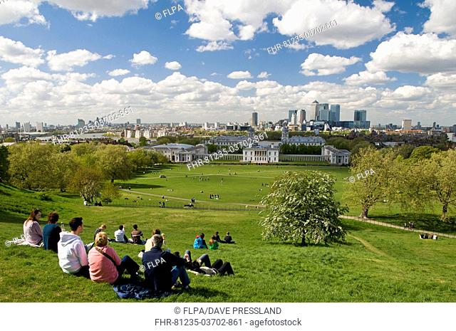 People sitting in park, visitors admiring view of National Maritime Museum, Queen's House, Royal Naval College and across River Thames to Docklands