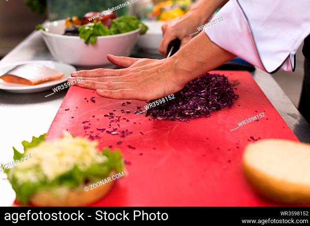 master chef hands cutting salad for a burger in the rastaurant kitchen