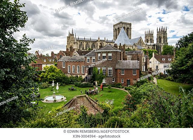 Dramatic clouds loom over the picturesque backyard garden with York Minster towering in the distance, York, Yorkshire, United Kingdom
