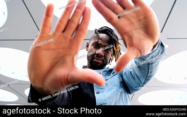 Man gesturing with palms under illuminated ceiling