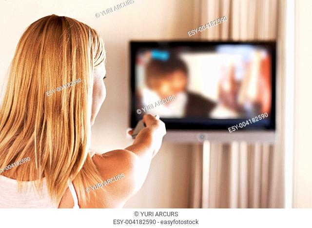 Image of young female swapping the televison channels using remote control at home