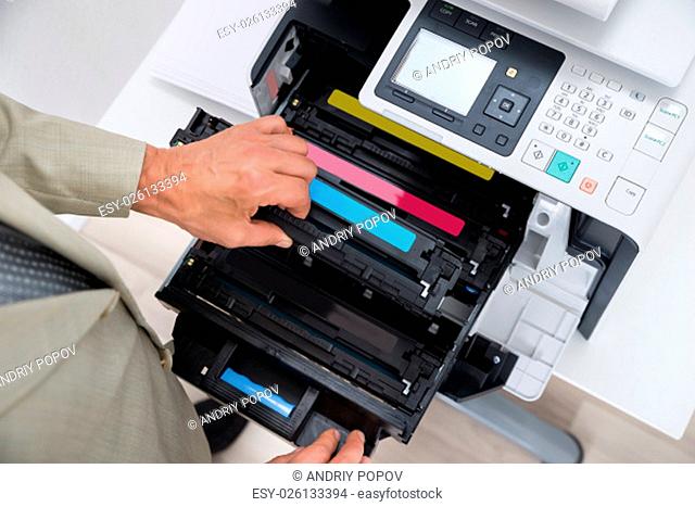 Cropped image of businessman fixing cartridge in photocopy machine at office