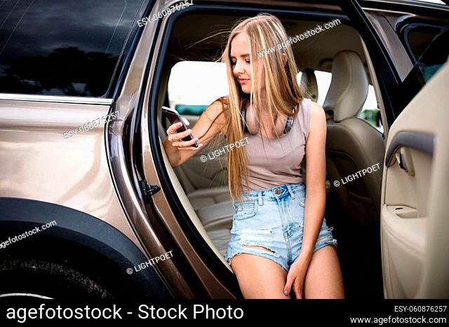Cute teenage girl with her smart phone during a roadtrip