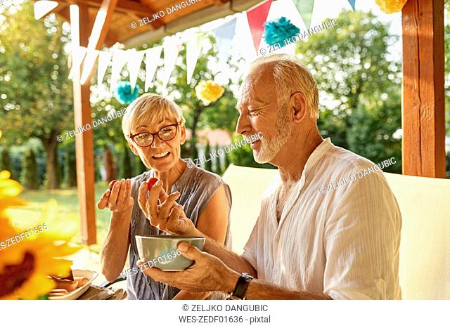Senior couple eating tomatoes on a garden party