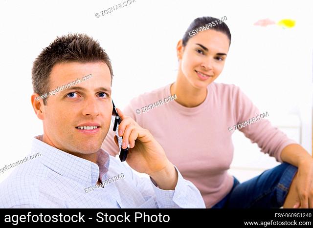 Man talking on mobile phone with her girlfriend in the background. Selective focus on man